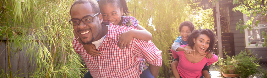 Family of four with children riding piggy back on parent's back